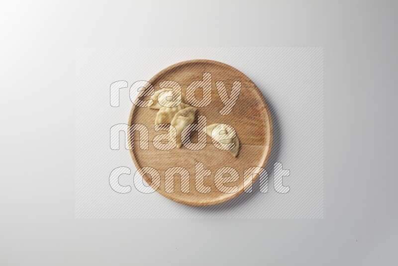 Four Sambosas on a wooden round plate on a white background