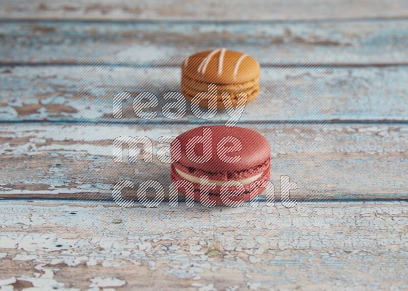 45º Shot of of two assorted Brown Irish Cream, and Red Velvet macarons on light blue background