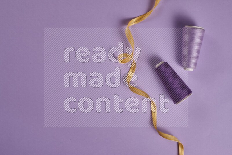 مجموعة من أدوات الخياطة والتفصيل صفراء وأرجوانية اللون على خلفية أرجوانية