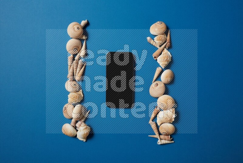 top view shot of phone with seashells on blue background