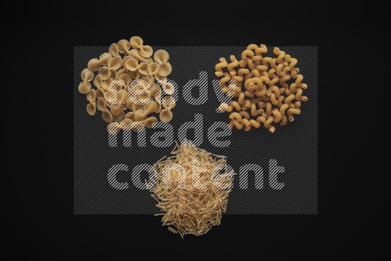 Different pasta types in bunches on black background