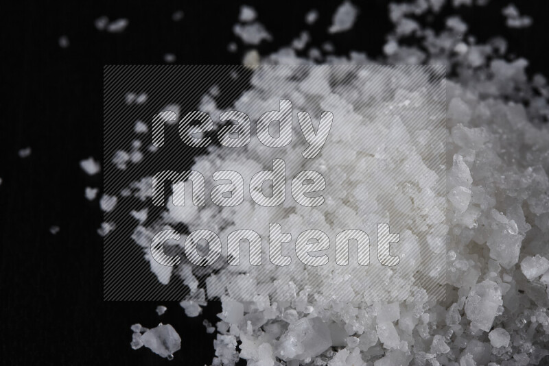 A bunch of coarse sea salt crystals on black background