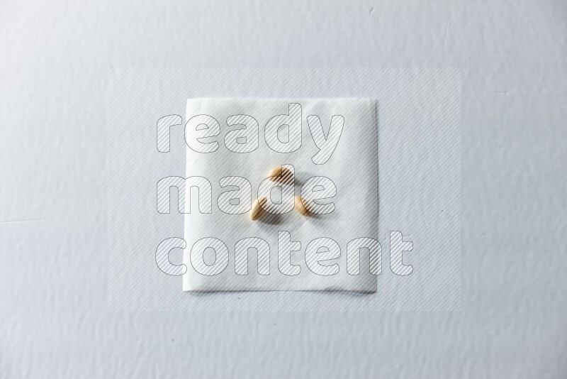 3 حبات من فول سوداني مقشرة على قطعة من الورق على خلفية بيضاء