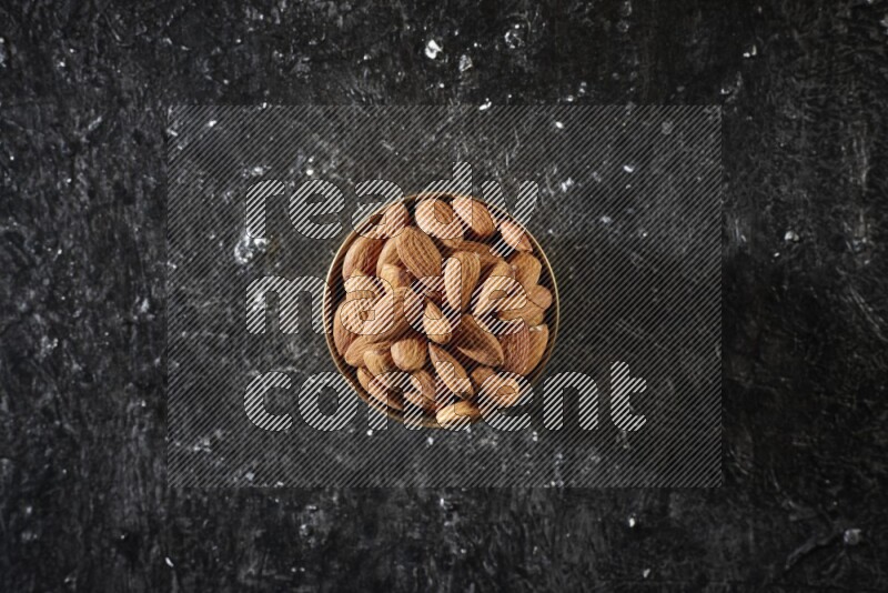 Nuts in a metal bowl in a dark setup