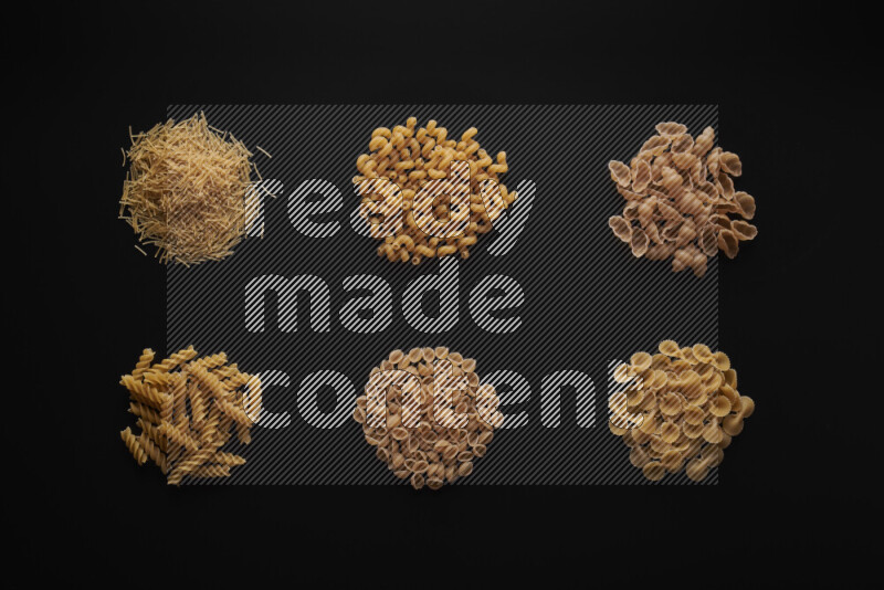 Different pasta types in bunches on black background