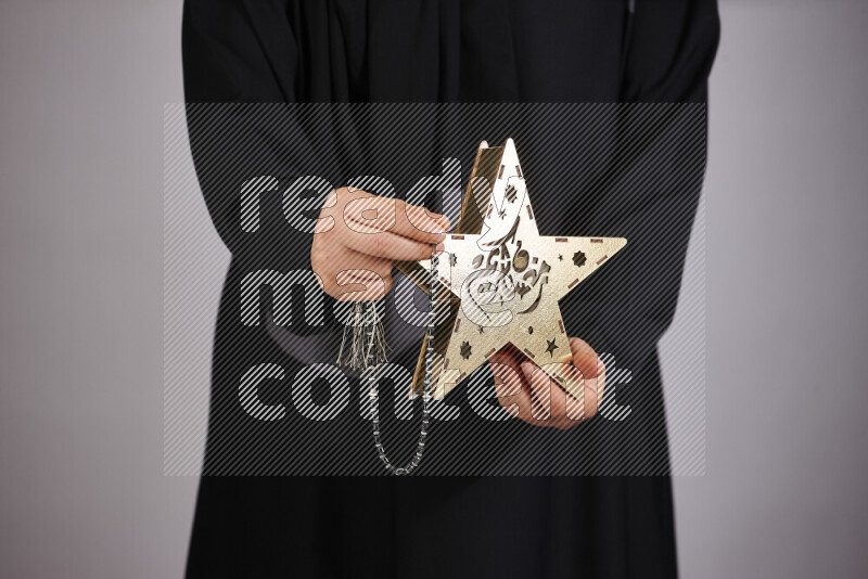 A woman in black abaya holding different ramadan lanterns in different positions