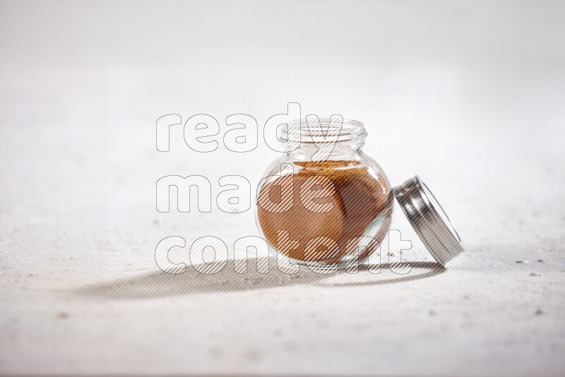 A glass jar full of ground paprika powder on white background