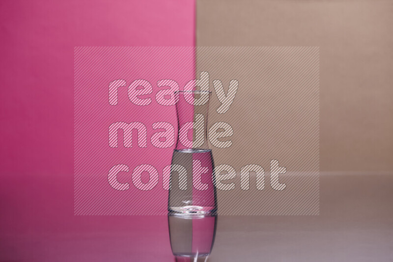 The image features a clear glassware filled with water, set against pink and beige background