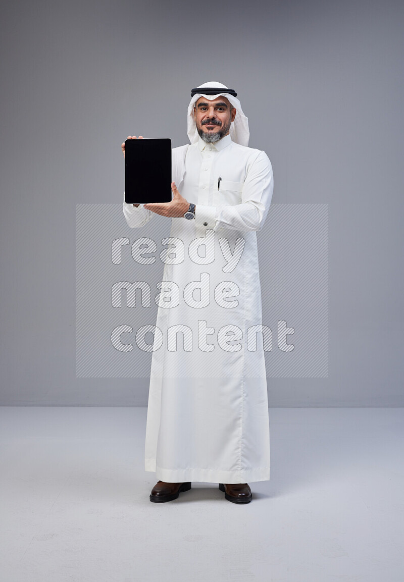 رجل سعودي يرتدي ثوب وشماغ ابيض ويحمل تابلت