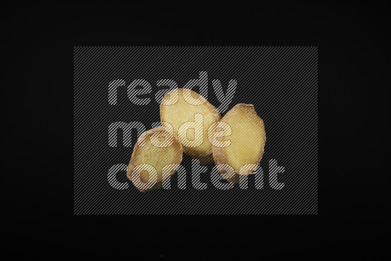 Fresh ginger slices on black background