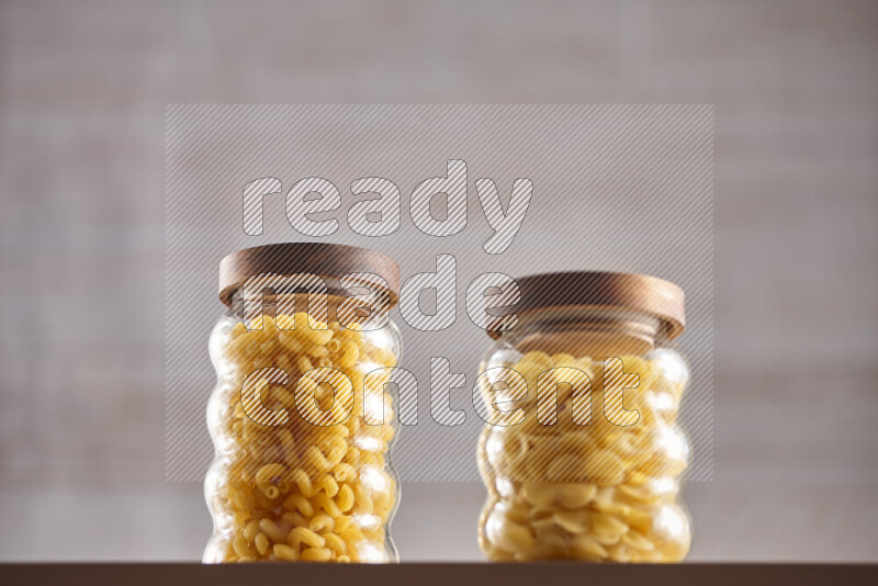 Raw pasta in glass jars on beige background