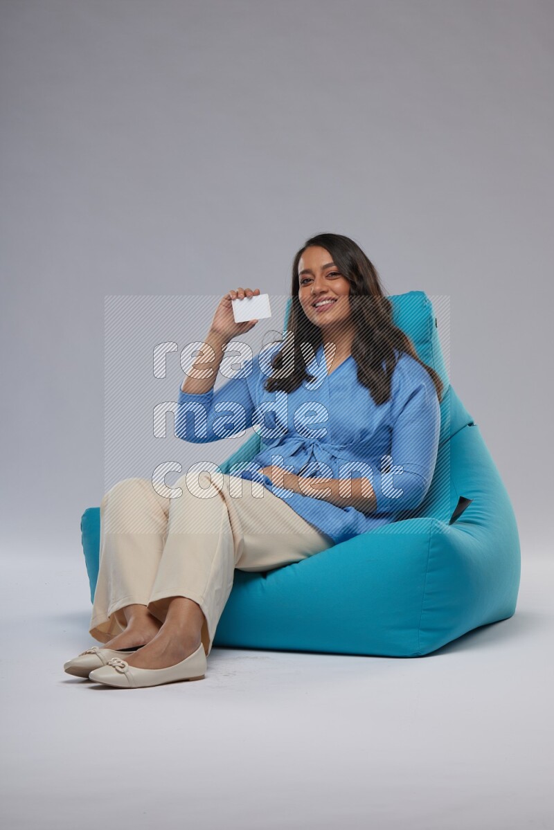 A woman sitting on a blue beanbag and holding ATM card