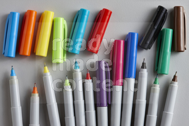 An arrangement of coloring pens in different colors on grey background