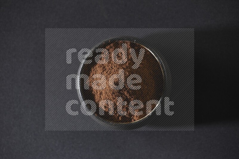 وعاء فخاري أسود ممتلئ ببودرة القرنفل علي خلفية سوداء