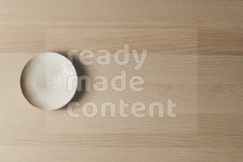 طبق من الفخار باللون البيج على خلفية خشبية فاتحة