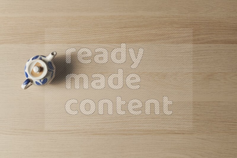 إبريق شاي فخاري على خلفية خشبية فاتحة