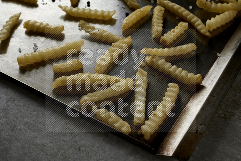crinkle fries in a black stainless steel rectangle tray on grey textured counter top