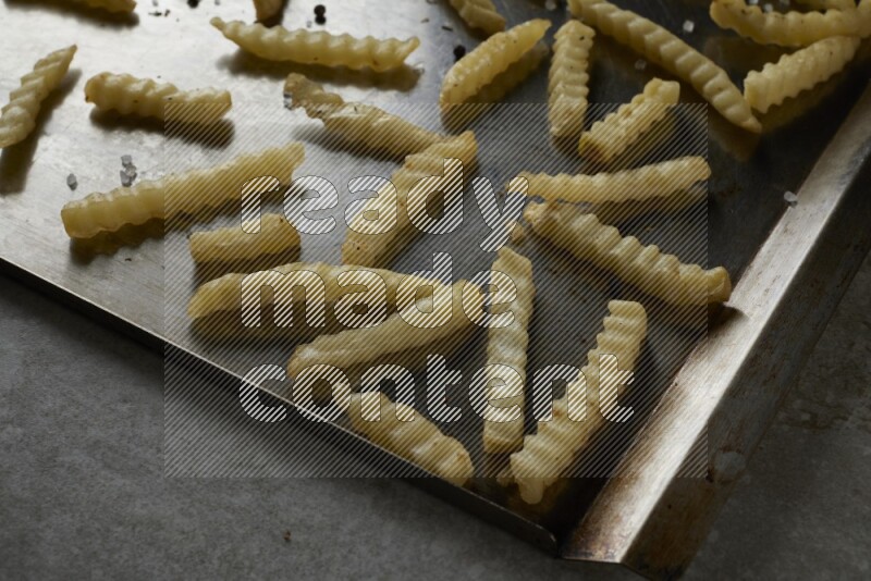 crinkle fries in a black stainless steel rectangle tray on grey textured counter top