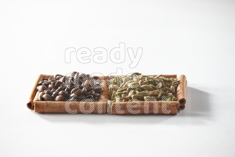 2 squares of cinnamon sticks full of cardamom and coffee beans on white flooring
