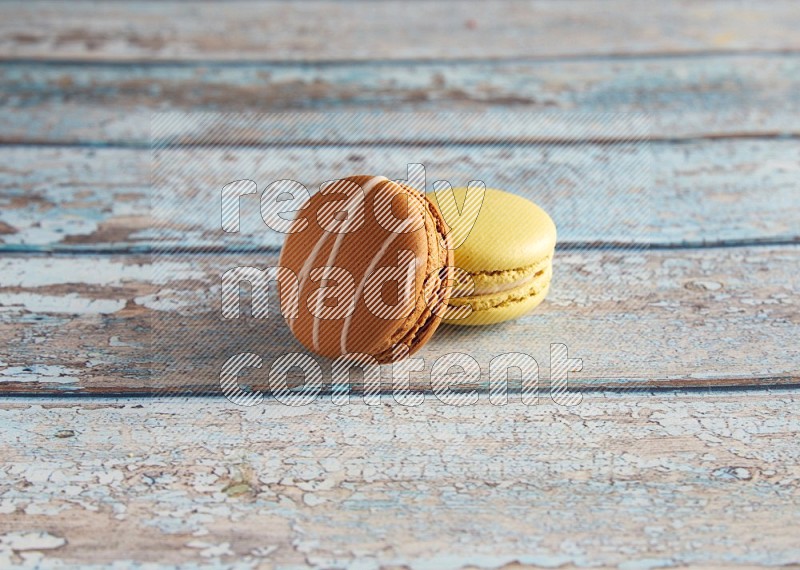 45º Shot of of two assorted Brown Irish Cream, and Yellow Lime macarons on light blue background