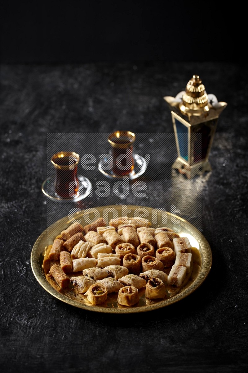 Oriental desserts with tea and a metal lantern in a dark setup