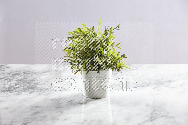 Green artificial plant in white pot on light grey marble background