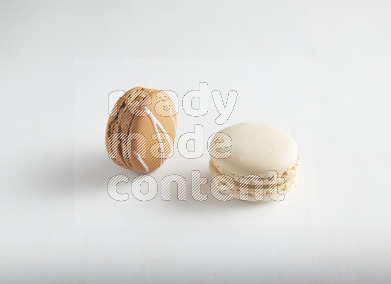 45º Shot of of two assorted Brown Irish Cream, and White Caramel fleur de sel macarons on white background