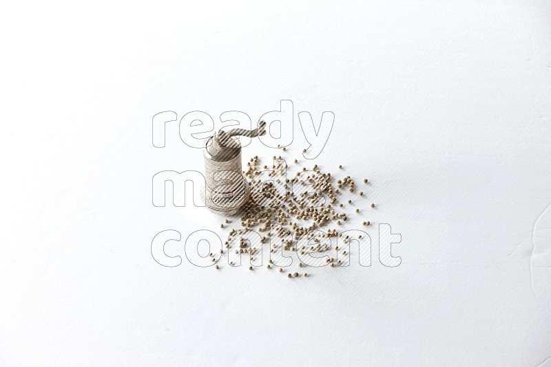 White pepper beads with a metal grinder on white flooring