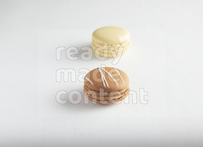 45º Shot of of two assorted Brown Irish Cream, and Yellow Vanilla macarons on white background