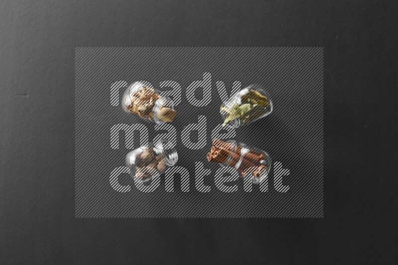 أوراق الغار وزنجبيل مجفف وقرفة وجوزة الطيب في أوعية زجاجية علي خلفية سوداء