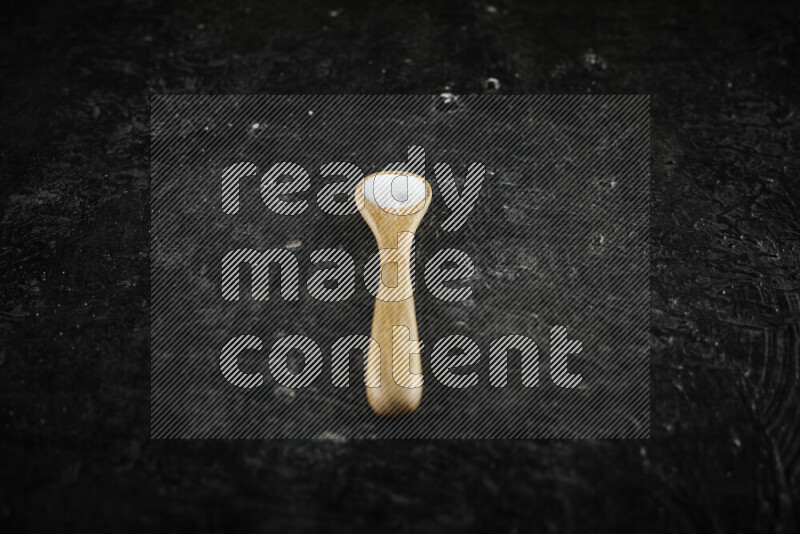 A wooden spoon full of white salt on black background