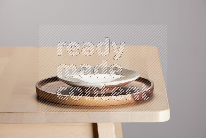 multi-colored pottery Plate placed on a light colored wooden tray on the edge of wooden table