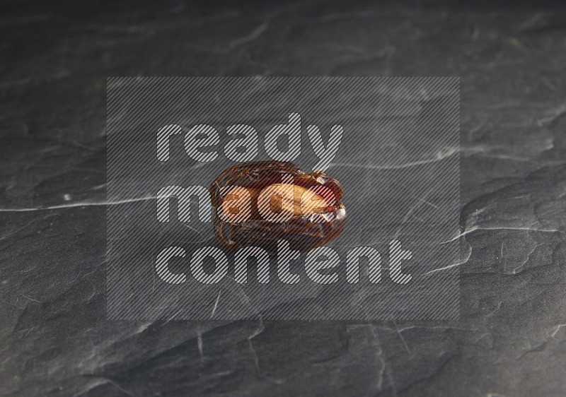 almond stuffed madjoul date on a black textured background