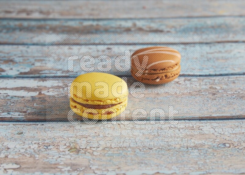 45º Shot of of two assorted Brown Irish Cream, and Yellow Lemon macarons on light blue background