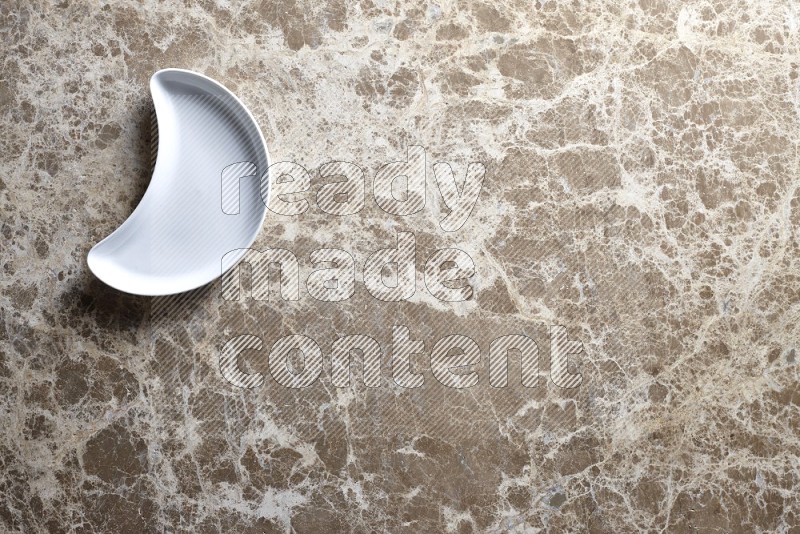 A pottery crescent plate on beige marble background