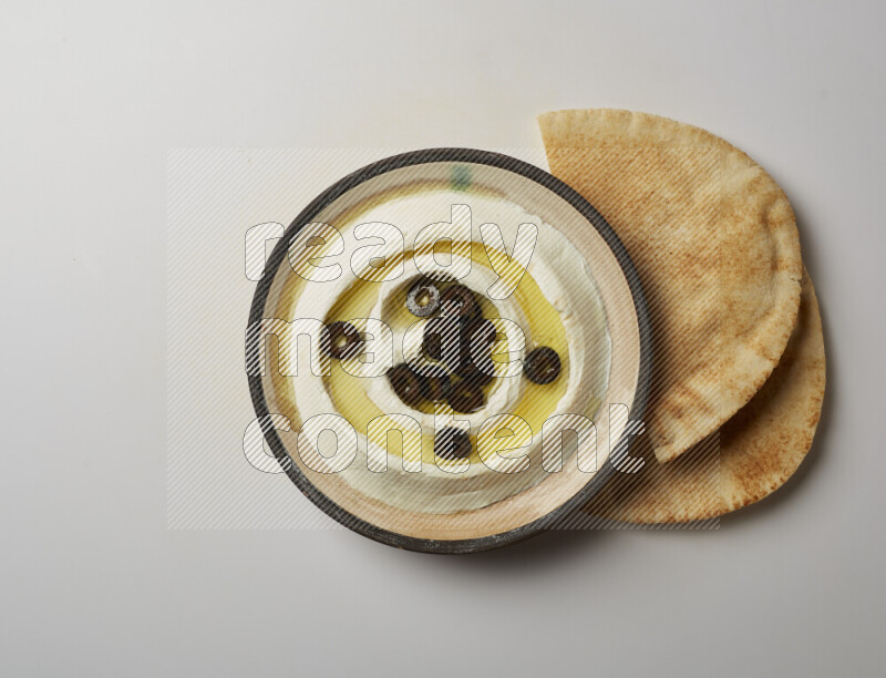Lebnah garnished with sliced olives in a pottery plate on a white background