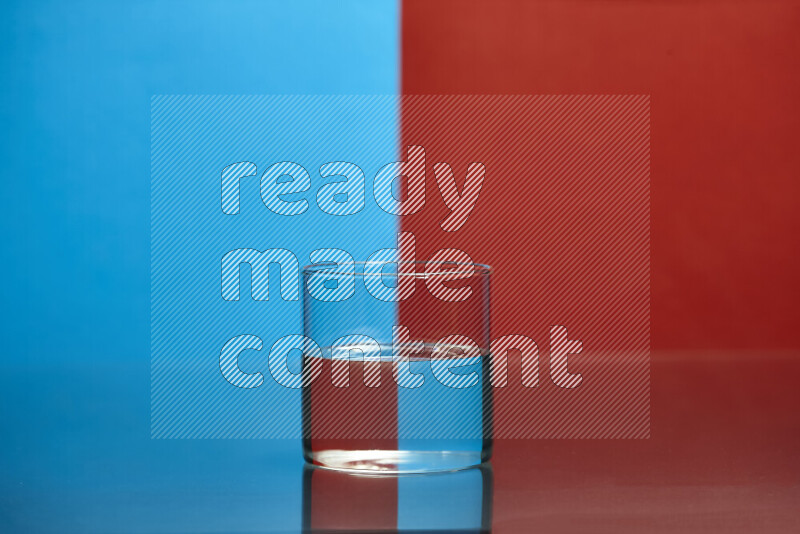 The image features a clear glassware filled with water, set against blue and red background