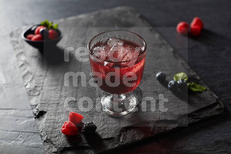 A glass of mixed berries juice on black background