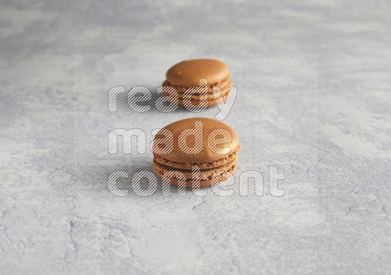 45º Shot of two Brown Coffee macarons  on white  marble background