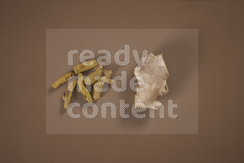 بهارات كاملة متنوعة تتضمن زنجبيل طازج ومجفف، أعواد قرفة، هيل، أصابع كركم، قرنفل، يانسون نجمي على خلفية بيج