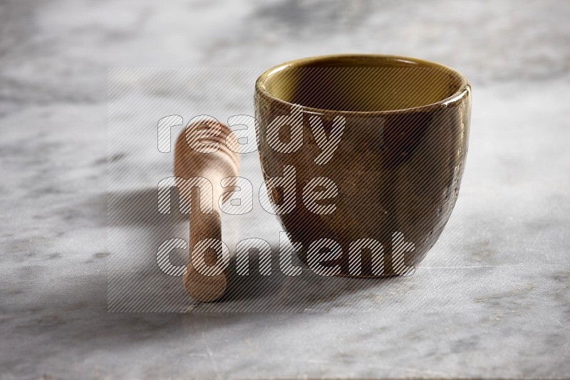 Multicolored Pottery cup with wooden honey handle on the side with grey marble flooring, 15 degree angle