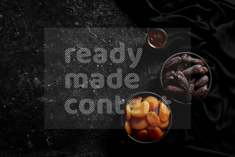 Dried fruits in pottery bowls with coffee in a dark setup