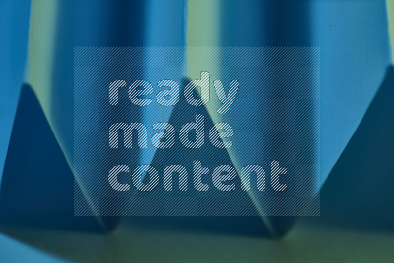 صورة مجردة مقربة تظهر طيات ورقية هندسية حادة بتدرجات اللون الأخضر والأزرق