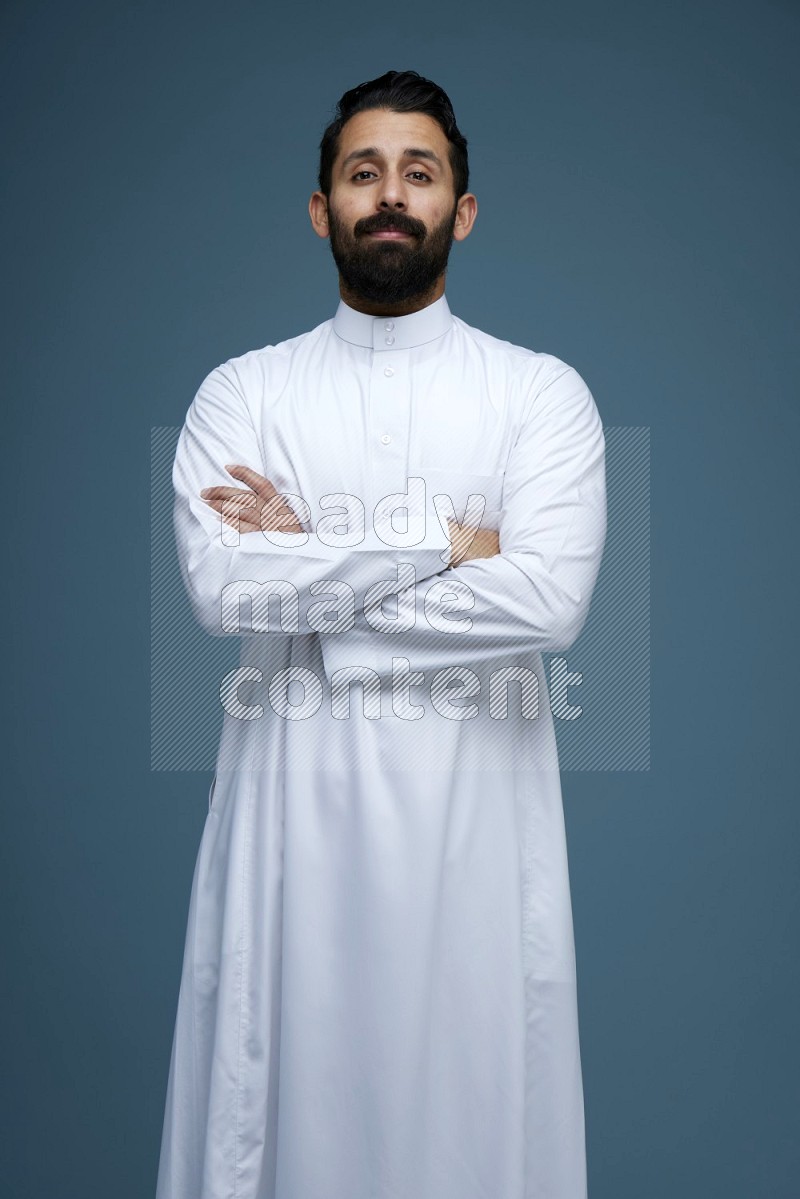 A man posing in a blue background wearing Saudi Thob