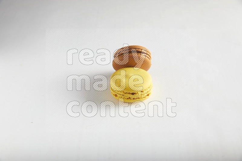 45º Shot of of two assorted Brown Irish Cream, and Yellow Lemon macarons on white background