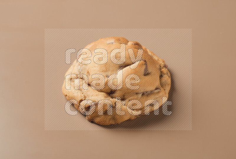 a whole chocolate chip cookie on a brown background