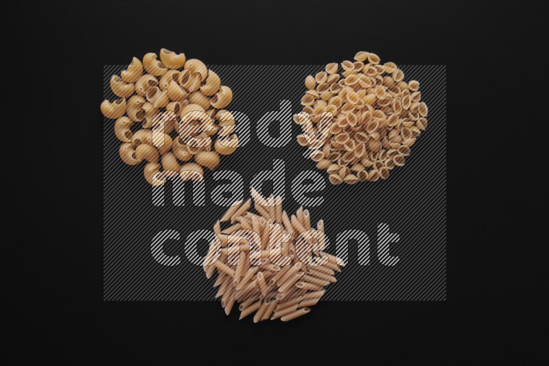 Different pasta types in bunches on black background