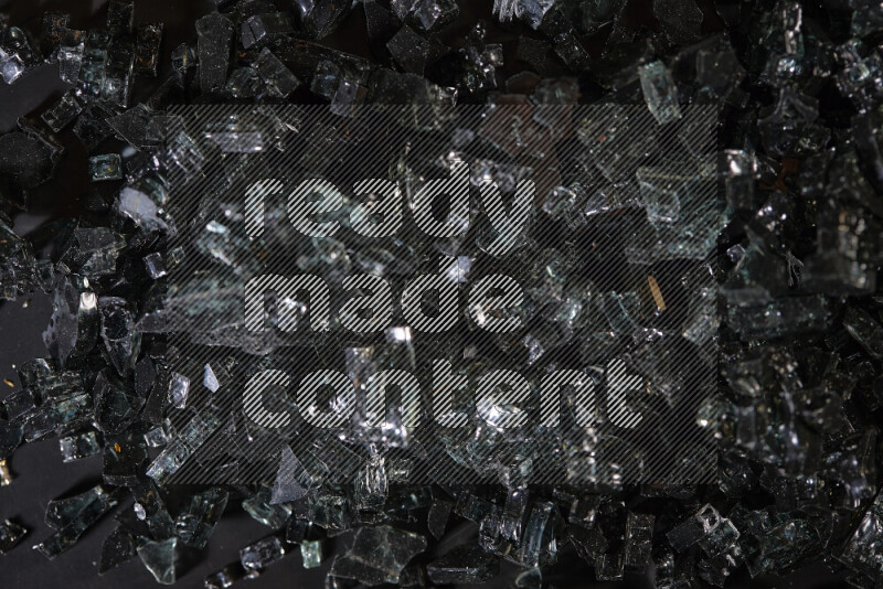 Transparent black fragments of glass scattered on a black background