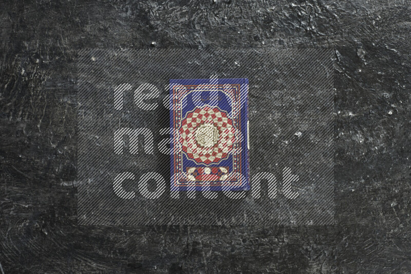 Quran with a prayer beads on textured black background