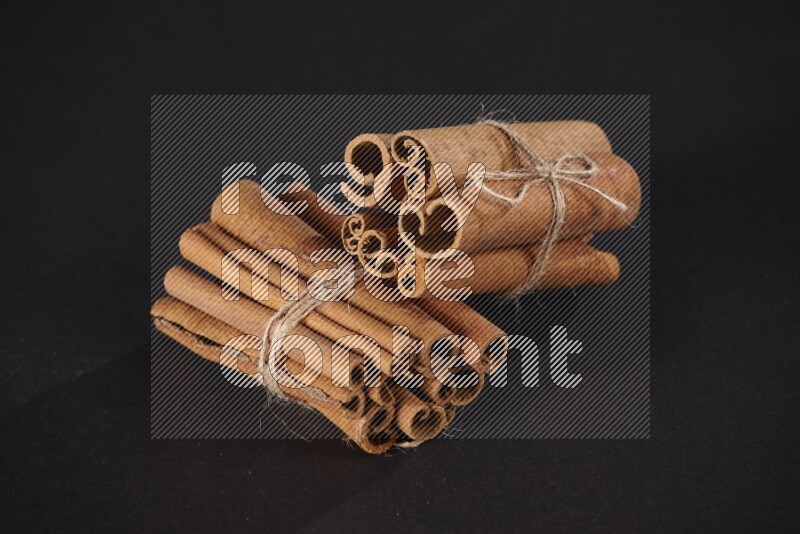 Two bounded stacks of cinnamon sticks on black background